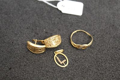 two gold rings and a pair of earrings on a black surface