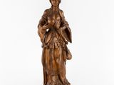 une statue en bois représentant une femme tenant un panier