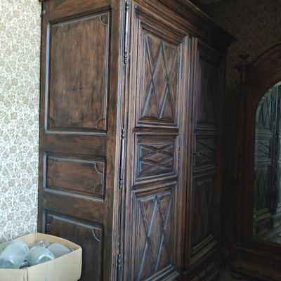 une grande armoire en bois avec un miroir, placée dans un coin