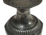 une assiette en argent posée sur un socle, sur fond blanc