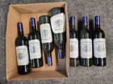 Plusieurs bouteilles de vin se trouvent dans un carton posé par terre.