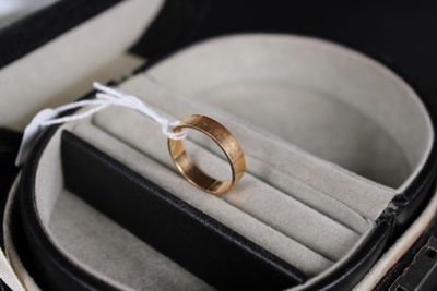 une alliance dans un écrin à bague, attachée à un cordon blanc