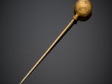 a gold stick with a ball on it on a black background