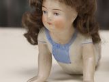 a small doll sitting on a table next to a teddy bear
