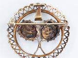 a gold brooch with two flowers and a bell on it
