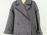 un manteau gris clair posé sur un mannequin, devant un fond blanc