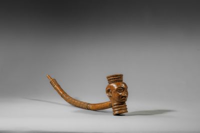 une image représentant une pipe en bois sur laquelle est gravé le visage d'un homme