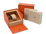 an orange box with a watch inside of it on a white surface