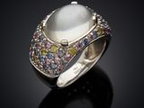 a close up of a ring with a white stone surrounded by multi colored stones