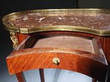 an antique wooden table with a marble top and brass trim