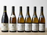 six bouteilles de vin sont alignées sur une table en bois