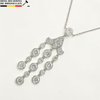 un gros plan d'un collier en diamants posé sur une surface blanche