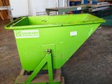 the green dumpster is sitting in the warehouse next to the other green bins