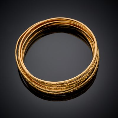 gros plan d'un bracelet en or sur une surface noire