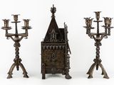 three metal candelabs with candles and a clock on top of them