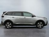 the silver car is parked in a parking lot near a white wall