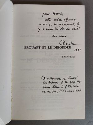 un livre ouvert, dont une page est recouverte d'une écriture manuscrite, posé sur une table