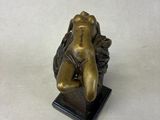 bronze statue of a woman sitting on top of a wooden base
