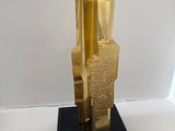 a gold sculpture on a black base on a white surface