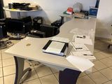 une table blanche sur laquelle est posé un ordinateur portable, dans une pièce