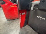 a red forklift parked in a warehouse with other red trucks in the background