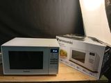 un micro-ondes blanc posé sur une table à côté d'une boîte de nourriture