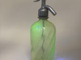 a green glass bottle with a metal spout on it