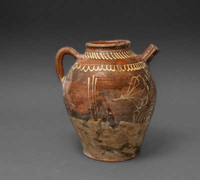 an old brown vase with designs on it on a gray surface