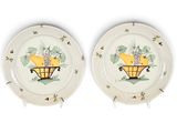 two plates with fruit painted on them on a white surface
