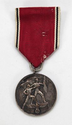 une vieille médaille ornée d'un ruban rouge et d'une médaille en argent sur fond blanc