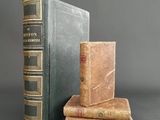 two old books are stacked on top of each other on a table