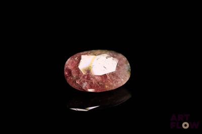 a close up of a pink diamond on a black surface