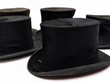 four black top hats are lined up on a white surface