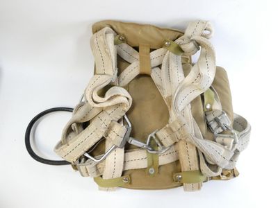 un sac à dos muni d'un harnais, posé sur une surface blanche