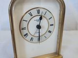 a small gold clock with roman numerals on it
