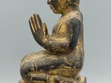 statue of a person sitting on a block with their hands clasped
