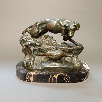 statue représentant un chien sautant par-dessus un rocher, posée sur un socle en marbre