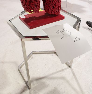 une petite table sur laquelle se trouve un vase rouge