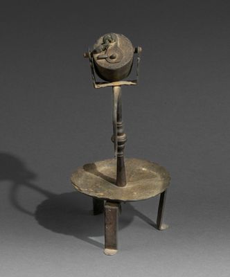 an old metal object on a stand with a shadow of a person