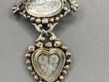 a close up of a necklace with a coin in the shape of a heart