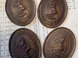 quatre pièces de monnaie anciennes en bronze posées sur un morceau de papier