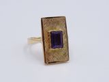 Gros plan sur une bague en or ornée d'une pierre violette.