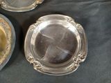 three silver plates are sitting on a table with a black cloth