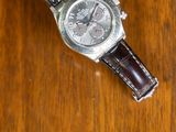 a watch sitting on a wooden table with a brown strap