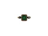 a close up of a ring with a green stone on it