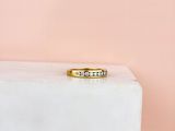 une bague en or sertie de trois diamants, posée sur un bloc de marbre blanc