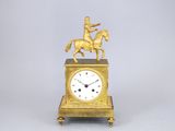 une horloge en or surmontée d'une statue représentant un homme à cheval