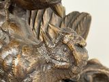 a bronze statue of a cat and a bird on a tree stump