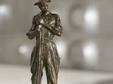 une statue en bronze représentant un homme tenant une pelle, posée sur une table