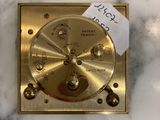 a gold clock on a marble table with a note pinned to it